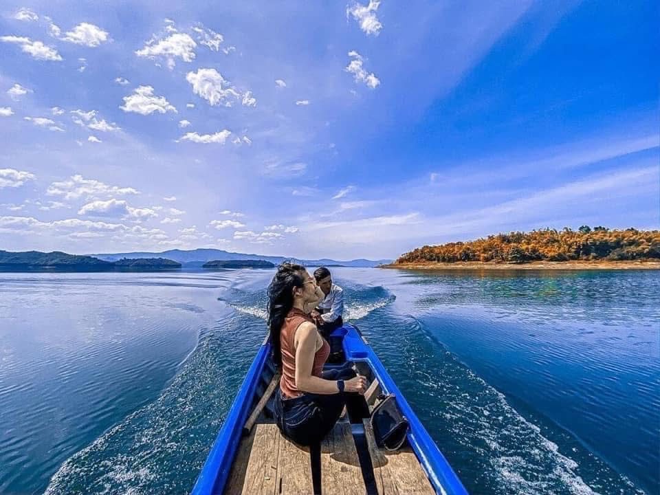 Du khách ngồi thuyền trên mặt hồ Tà Đùng trời xanh